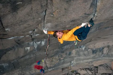 Ein Kletterer meistert eine anspruchsvolle **offwidth climbing** Route, seine Hände greifen fest in den Fels.