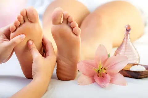 Un massage des pieds relaxant, avec une fleur de lys et une bougie. Découvrez les bienfaits du massage pieds pour votre bien-être.