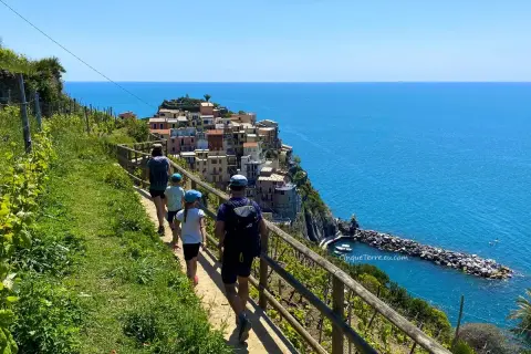 Familj på en vacker cinque terre vandring längs kusten med färgglada hus och blått hav.