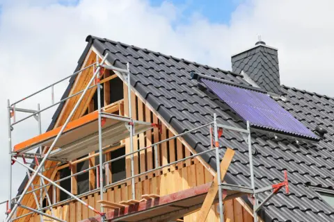 Gerüst am Dach eines Hauses, das saniert wird. Solarkollektoren sind installiert.