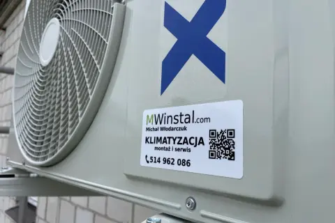 Zewnętrzna jednostka klimatyzatora z naklejką firmy MWinstal.com.