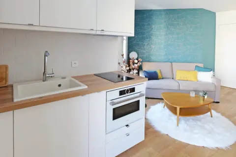 Plan d'une petite cuisine en U moderne avec évier, plaque de cuisson, four et un salon cosy avec canapé bleu et jaune.
