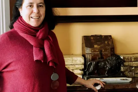 Una mujer sonríe junto a una estatuilla de león y libros antiguos, quizás en un salón de **Loyola de Palacio**.