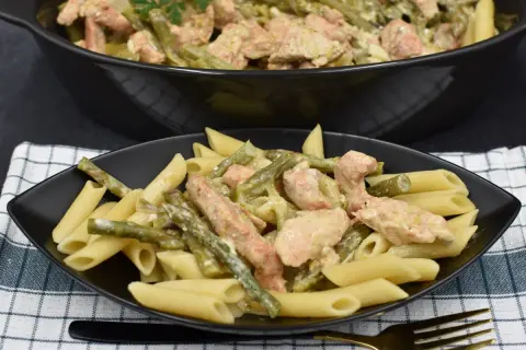 Penne z kurczakiem i szparagami w kremowym sosie. Pyszne danie na talerzu i w garnku.