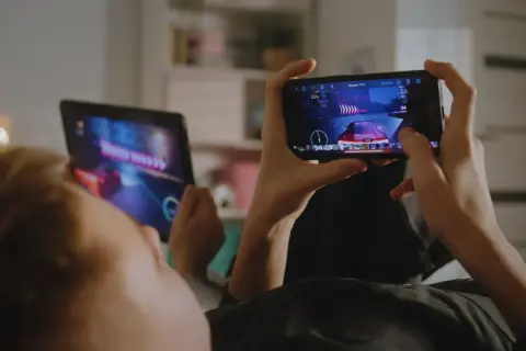 Dzieci grają w fajne gry na telefonie i tablecie, ścigając się w wirtualnym świecie.