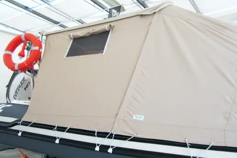 Tenda campeggio nautico su gommone, con oblò e salvagente arancione.