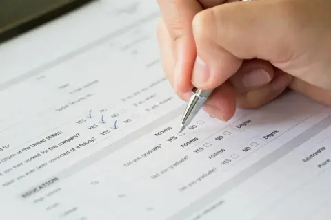 Dłoń z długopisem wypełnia formularz, zaznaczając odpowiedzi. Kluczowe jest tu prawidłowe wypełnienie dokumentu, np. identyfikacja zobowiązania PCC-3.