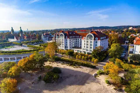 Hotel Sheraton Sopot z widokiem na plażę i jesienne drzewa.