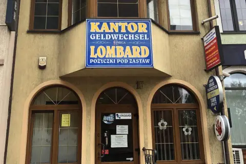 Elewacja budynku z szyldem "KANTOR GELDWECHSEL LOMBARD POŻYCZKI POD ZASTAW".