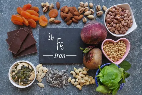 Una tavola ricca di alimenti ricchi di ferro: cioccolato fondente, albicocche, mandorle, pistacchi, barbabietole, fagioli, soia, spinaci, semi di zucca e girasole.