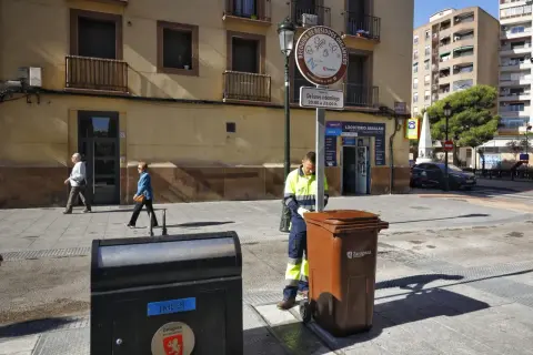 Un trabajador recoge un contenedor marrón en Zaragoza, bajo un sol radiante, como parte de la fiesta del sol.