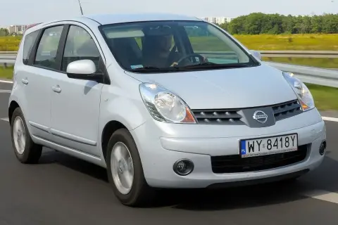 Srebrny Nissan Note E11 w ruchu drogowym. Kierowca w czapce prowadzi auto po asfaltowej drodze.