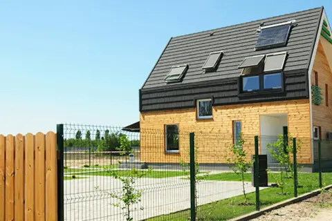 Nowoczesny dom z drewnianą elewacją i panelami słonecznymi na dachu. To ekologiczne rozwiązanie, przypominające trochę earthship, z pewnością przyciąga wzrok.