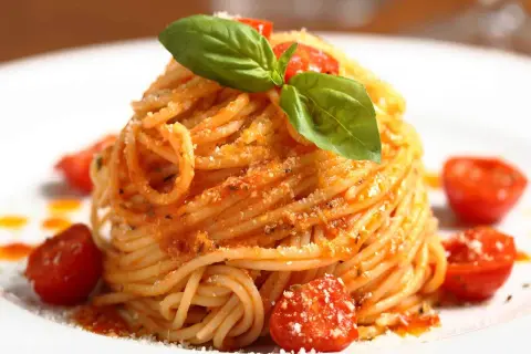 Ein Teller mit köstlichen Spaghetti Aglio e Olio, garniert mit frischem Basilikum und Kirschtomaten.