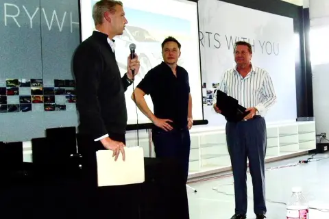 Elon Musk, jeden z tych, kto stworzył Teslę, stoi obok dwóch mężczyzn podczas prezentacji.