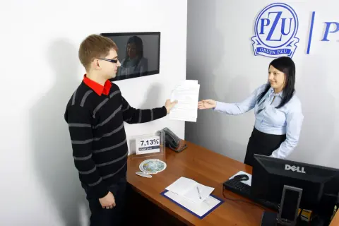 Mężczyzna podaje dokumenty kobiecie przy biurku w biurze PZU.