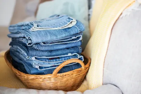 Stapel blauer Jeans in einem Korb. Die Frage, wie oft Jeans waschen, beschäftigt viele.
