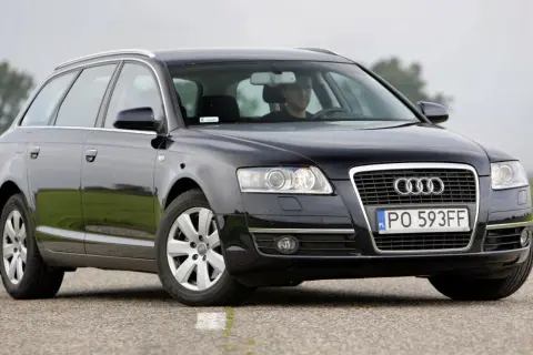 Audi A6 C6 kombi, przygotowanie do wymiany żarówki do jazdy dziennej. Kierowca w kabinie.