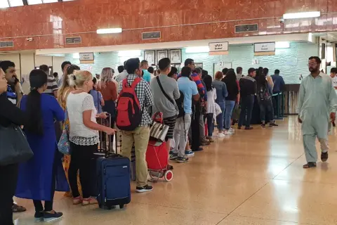 Kolejka podróżnych w hali odlotów, być może na lotnisku AUH Zayed International, oczekujących na odprawę.