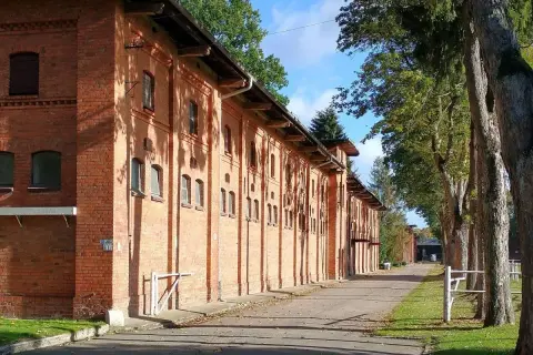 Długa, ceglana stajnia w Starogardzie Gdańskim, gdzie kiedyś stacjonował stado ogierów. Aleja drzew prowadzi do budynków.