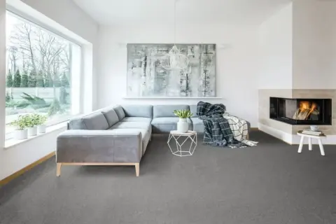 Nowoczesny salon z szarą wykładziną na ogrzewanie podłogowe, wygodną kanapą i kominkiem.
