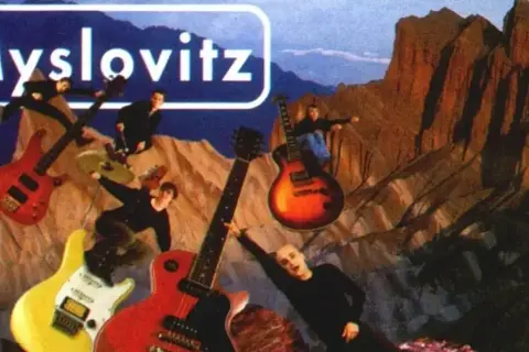 Myslovitz - miłość w czasach popkultury. Członkowie zespołu na tle gór, otoczeni gitarami, jakby w kosmicznej podróży.