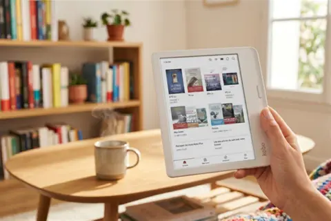Une personne utilise une liseuse pour obtenir la version numérique d'un livre acheté, dans un salon cosy avec des livres et une tasse de café fumante.