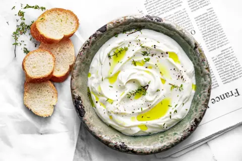 Labneh co to? Kremowy serek jogurtowy z oliwą, pieprzem i tymiankiem, podany z chrupiącymi grzankami. Idealny na śniadanie lub przekąskę.