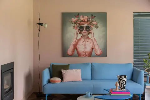 Peinture pièce de vie : un tableau surréaliste d'une femme aux lunettes et couronnes de fruits, sur un canapé bleu vif.