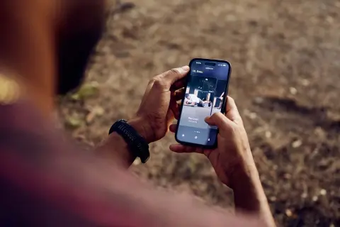 Une application de fitness running s'affiche sur un smartphone tenu par une personne.