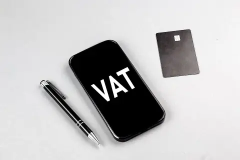 Telefon z napisem VAT, obok długopis i karta płatnicza. Ułatwia to ptu rejestracja.