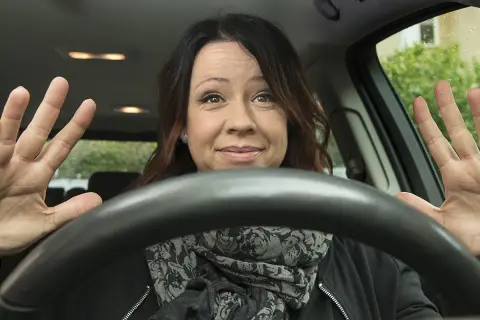 Kvinna visar hur man ska hålla ratten med båda händerna, redo att köra.