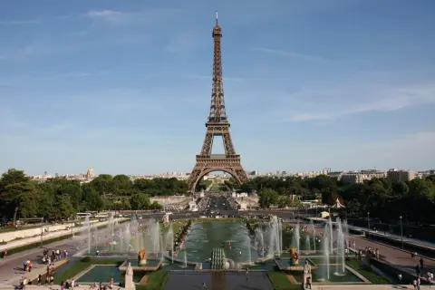 La Tour Eiffel se dresse fièrement, invitant à la découvrir. Des fontaines jaillissent, des gens se promènent, une belle journée pour monter à la Tour Eiffel.