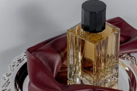 Eleganckie perfumy z lat 2000. w szklanej butelce z czarną nakrętką, na ozdobnej tacy z bordową skórką.