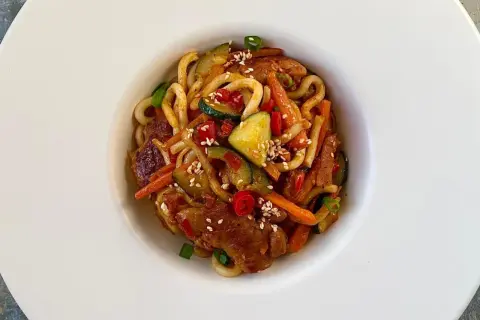 Szybki i tani obiad: makaron udon z kurczakiem, cukinią, marchewką i papryką, posypany sezamem.