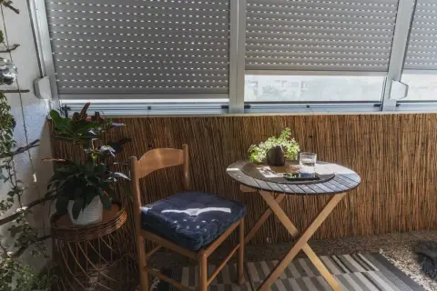 Przytulna loggia z drewnianym krzesłem, stolikiem i roślinami. Idealne miejsce na poranną kawę.