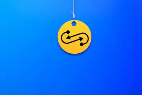 Żółty krążek z symbolem nieskończoności i strzałkami, wiszący na nitce. Czy to symbolizuje swap?