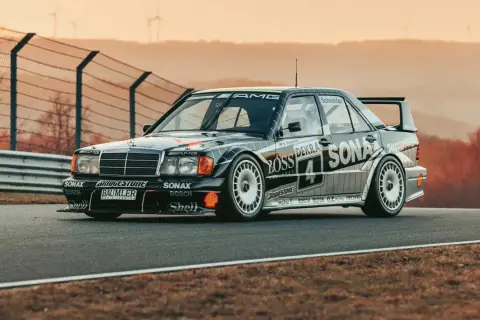 Czarny Mercedes 190 Evo na torze wyścigowym, z licznymi sponsorami na karoserii, gotowy do startu.