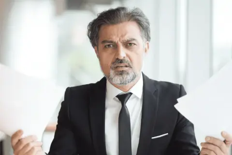 Hombre con traje y papeles, preocupado por cuanto cobra una inmobiliaria por alquilar un piso.