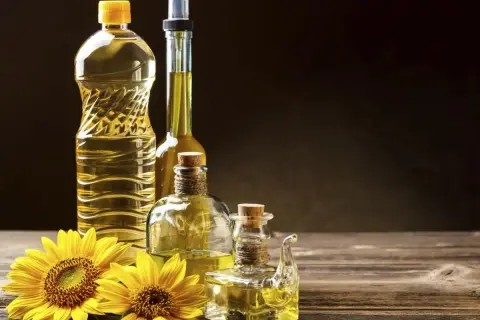 Bottiglie di olio di semi e girasoli. Si può mischiare l'olio d'oliva con l'olio di semi per un sapore unico.