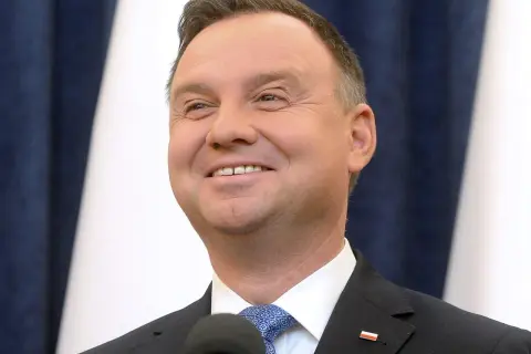 Uśmiechnięty Andrzej Duda, jego wiek nie jest widoczny na zdjęciu, ale wygląda na dojrzałego mężczyznę w garniturze.