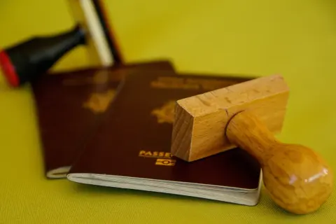 Stempel nad paszportem, symbolizujący biurokrację i potencjalną deportację.