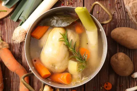 Un plat mijoté de poule au pot, avec carottes, poireaux et pommes de terre, prêt à être dégusté.