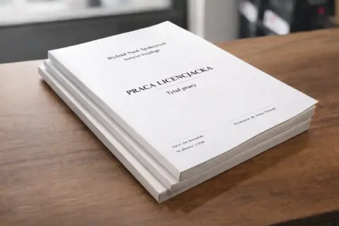 Stos białych prac licencjackich na drewnianym blacie. Na okładce widnieje tytuł "Praca licencjacka", imię autora i promotora.