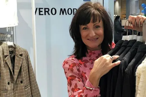 Kvinna i blommig blus vid klädställning med plagg från Vero Moda rea.