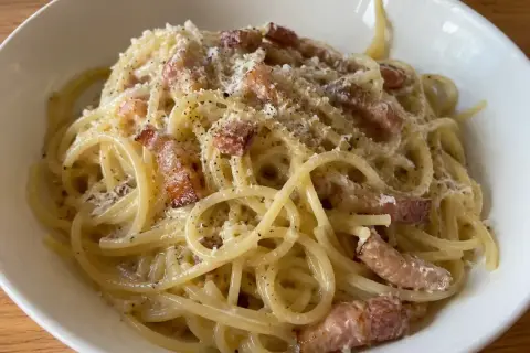 En krämig portion pasta carbonara med knapriga bitar av fläsk och rikligt med svartpeppar.