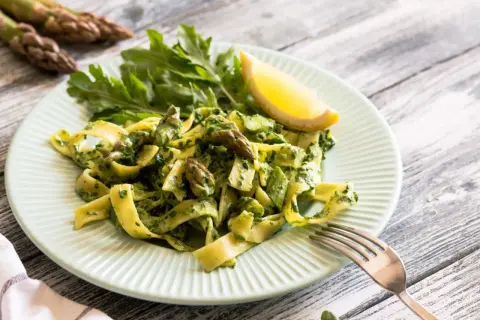 Pappardelle ze szparagami i zielonym pesto, udekorowane rukolą i cytryną. Pyszne danie, które zachwyci każdego miłośnika makaronu.