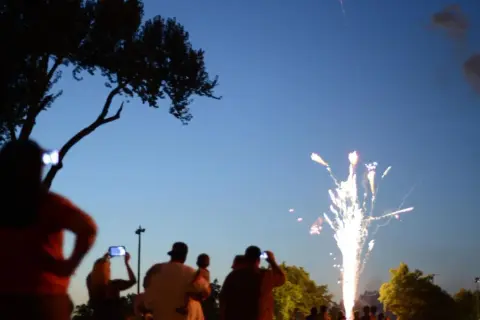 Gente observa fuegos artificiales, como en las mejores ferias de España.