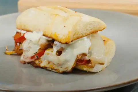 En saftig philly steak sandwich med smält ost och paprika på en tallrik.