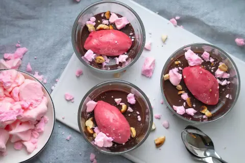 Tre glas med chokladmousse toppas med rosa sorbet, krossad maräng och nötter. Dessa goda desserter ser aptitliga ut!